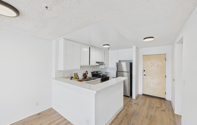 A kitchen with white cabinets and a wooden floor.