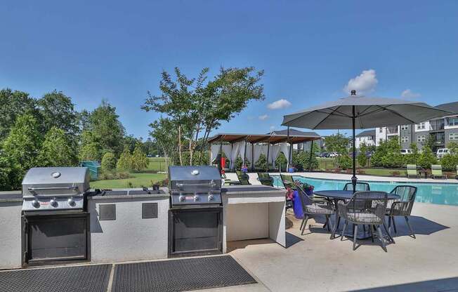 A patio with a grill, table, and chairs.