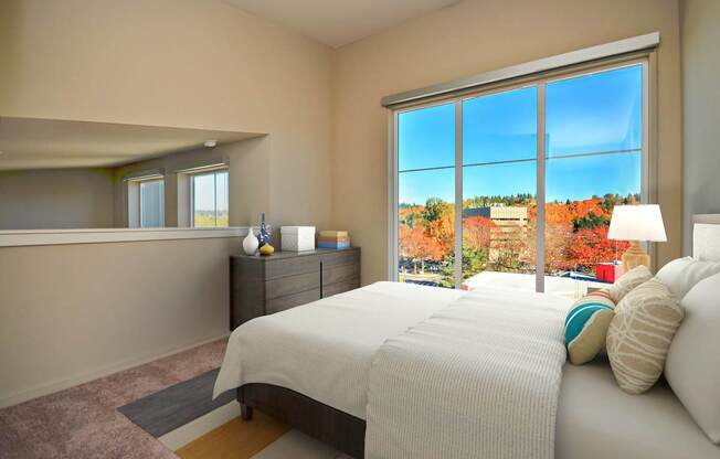 A bedroom with a large bed and a view of the outdoors through a large window.