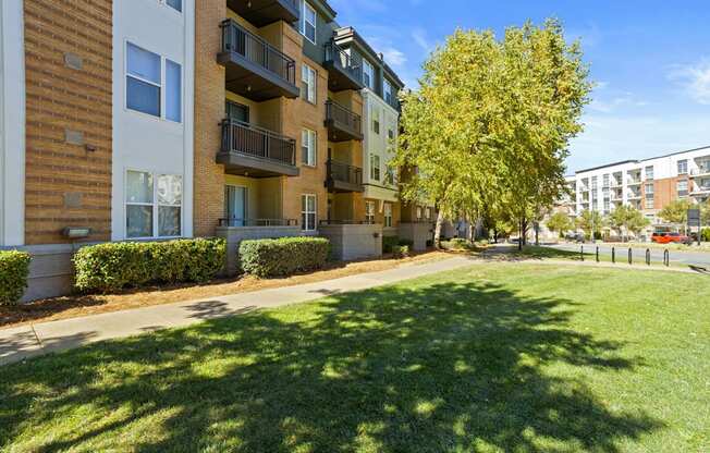 Flatiron West Trade Apartments green space outside of 4-story apartments with balconies