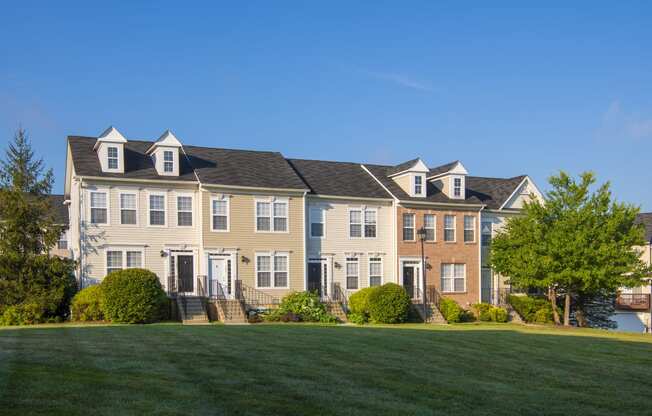 a row of houses on a green lawn with a blue sky