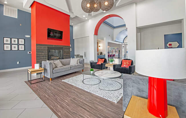 a living room with gray couches and a red accent wall