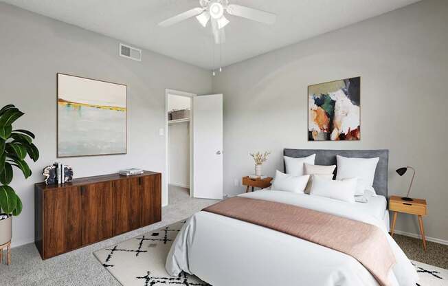 A carpeted bedroom with a large bed, ceiling fan, and a wooden dresser at Jefferson Creek Apartments in Irving, TX