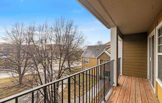 A balcony with a black railing and a wooden floor.