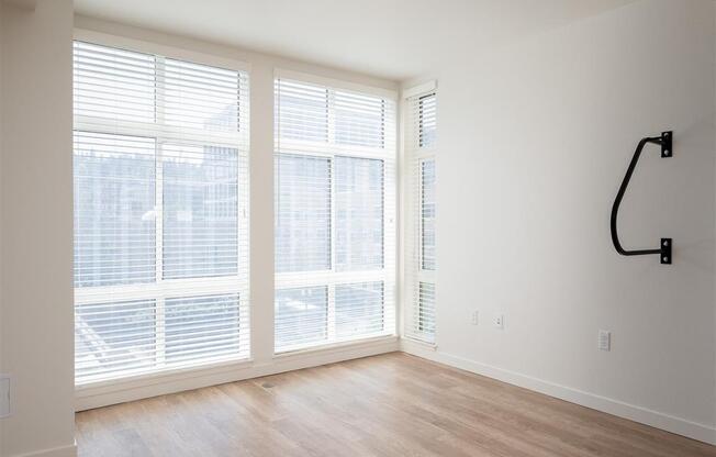 an empty living room with large windows and a wood floor