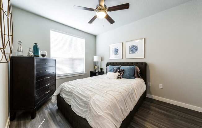 Bedroom one with wood-style flooring, ceiling fan and large bedside window