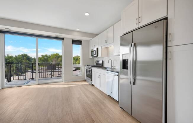 a kitchen with white cabinets and stainless steel appliances and a sliding glass door that leads to a