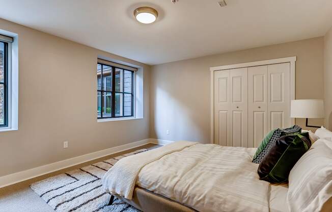 A bedroom with a bed, pillows, and a striped rug.