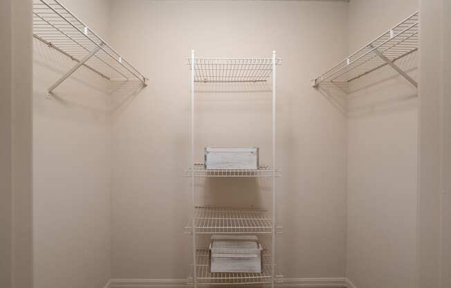 a walk in closet in a small room with white walls and white shelves and racks