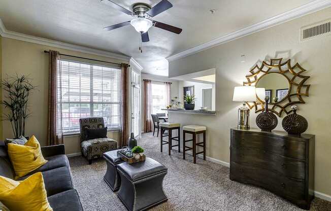 A living room with a grey couch, yellow pillows, and a ceiling fan.