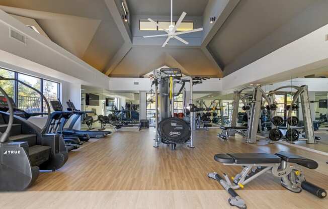 a gym with weights and cardio machines and a ceiling fan