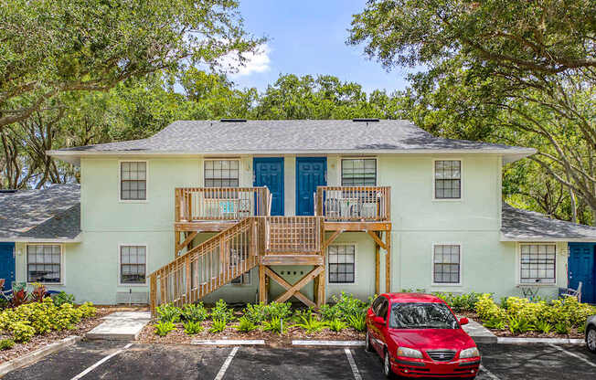 A two-story house with a red car parked in front.