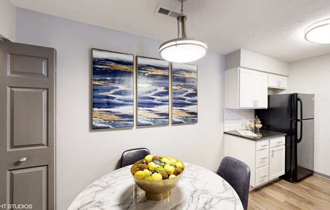 a kitchen and dining room with a bowl of fruit on the table