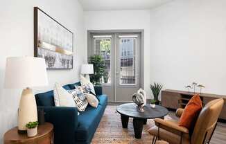 A living room with a blue couch, a coffee table, and a painting on the wall.