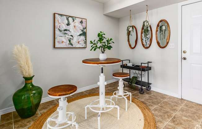 A green vase sits on a white table in a room with a white wall and a painting hanging on it.