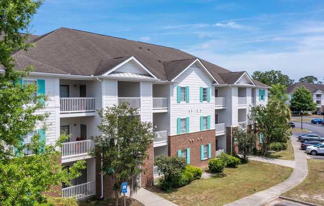 A white apartment building with green shutters on the windows at The Palms at Chatham apartments in Savannah GA.