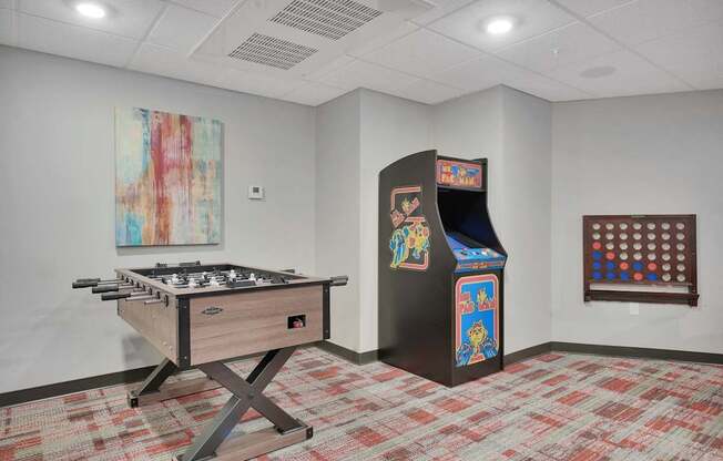 A room with a pool table, a pinball machine, and a painting on the wall.