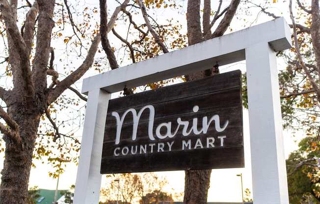 A sign for Marin Country Mart is displayed on a tree.