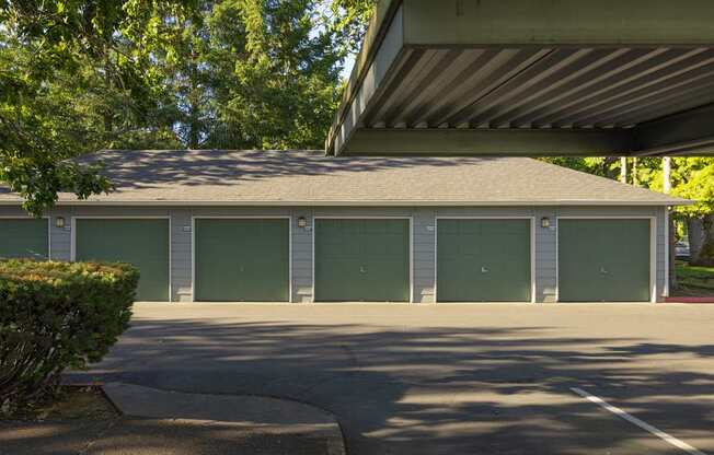 A building with a grey roof and green garage doors.