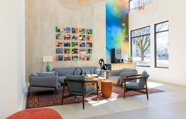 A living room with a grey couch, a green chair, a brown table and a wall with pictures.