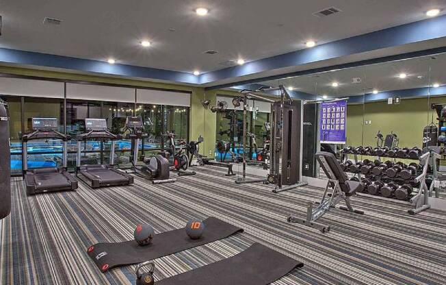 a fitness center with a lot of weights on the floor at Hunters Creek Apartments, Denton, TX