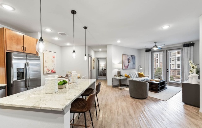 an open kitchen and living room with a marble counter top