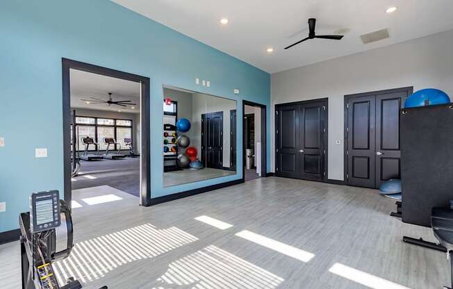 A spacious room with a mirror, exercise equipment, and a ceiling fan.
