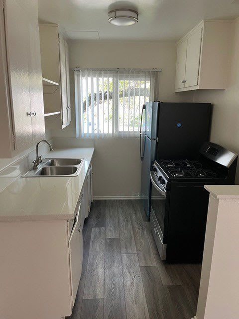 Kitchen with wood plank style flooring, white cabinets, and gas range at Los Robles Apartments in Pasadena, California.