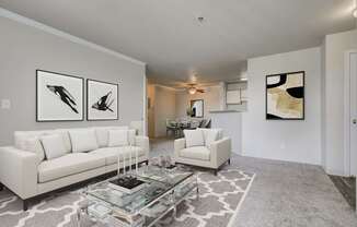 A living room with a white couch, a coffee table, and two framed pictures on the wall.