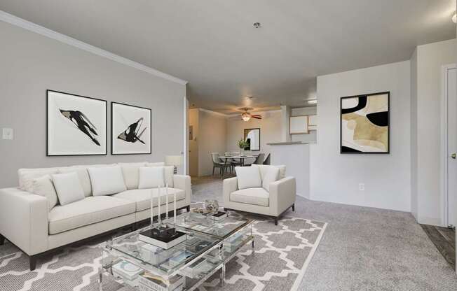 A living room with a white couch, a coffee table, and two framed pictures on the wall.