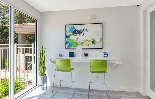 a home office with green chairs and a white desk and a painting on the wall