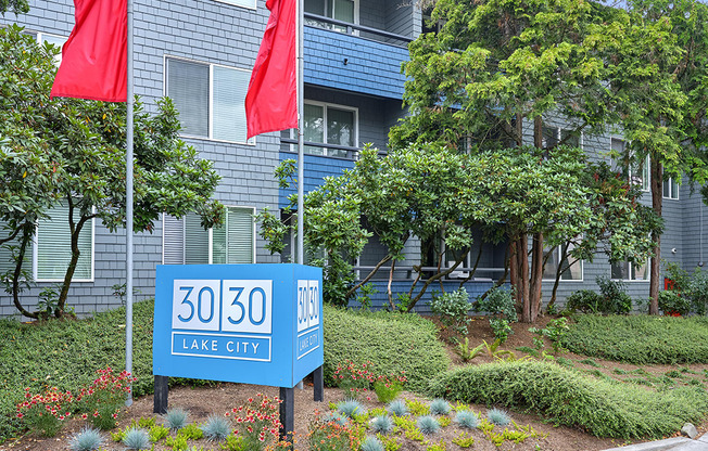 a large blue apartment building with two red flags in front of it  at 3030 Lake City, Seattle, Washington