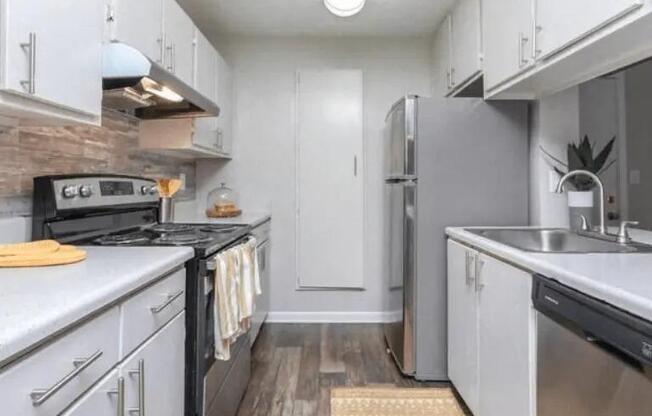 a white kitchen with stainless steel appliances and white cabinets at The Sapphire, Decatur, Georgia