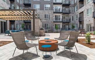 a patio with chairs and a table in front of an apartment building