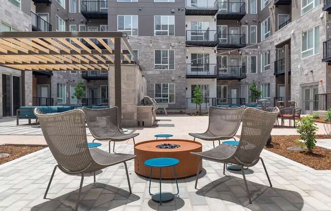 a patio with chairs and a table in front of an apartment building