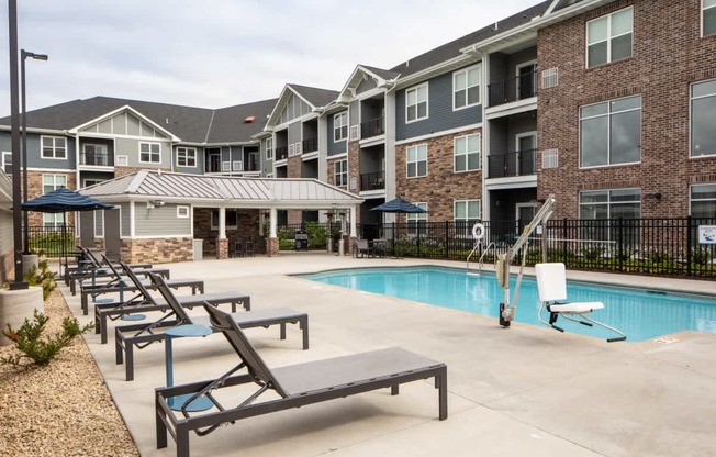 A pool area with sun loungers and a slide in front of apartment buildings.