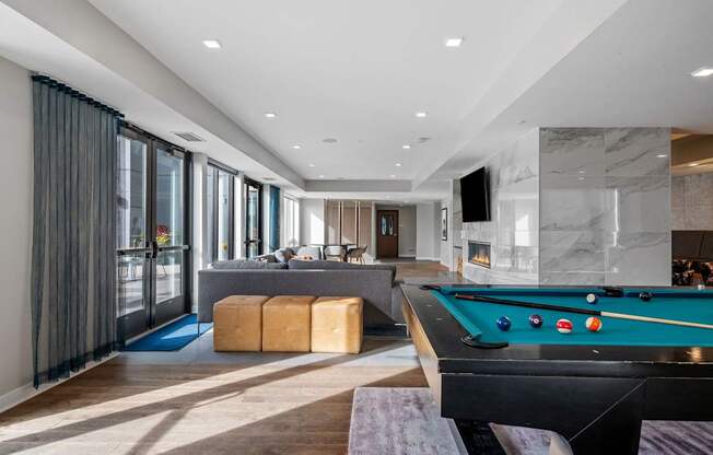 A pool table is in the middle of a room with a bar and a television.