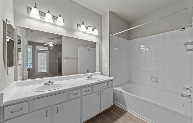 A bathroom with a white tub, sink, and mirror.