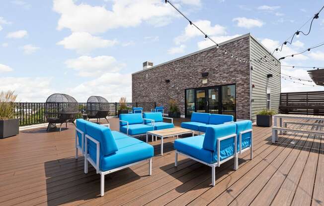 a rooftop patio with blue chairs and a brick building at the vue apartments in indianapolis