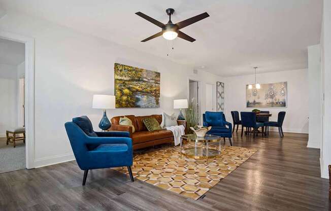 A living room with a blue chair and a painting on the wall.