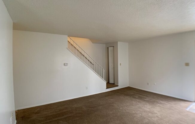 Large carpeted living room with stairs