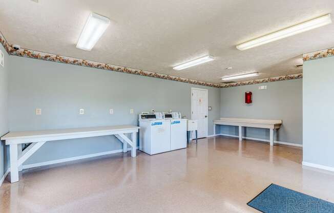 an empty room with two benches and two washing machines