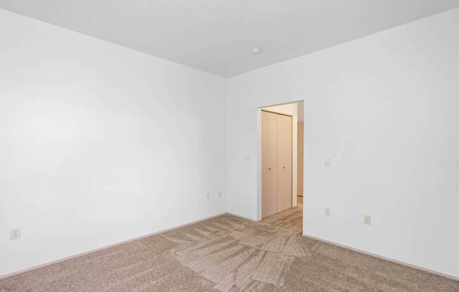 a bedroom with white walls and a door to a closet