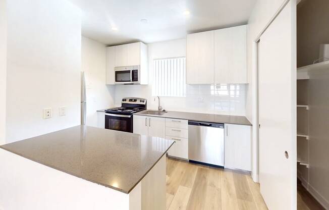 A modern kitchen with a stainless steel countertop and white cabinets.