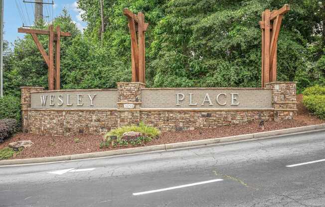 A sign that says Wesley Place is in front of a road.