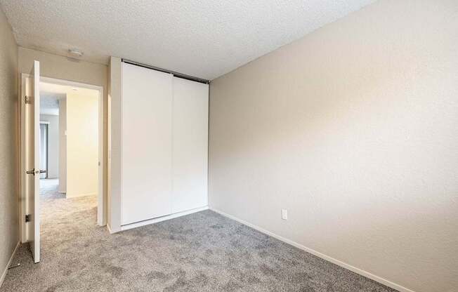 Bedroom with soft carpet and a sliding closet door inside a Peak 88 two-bedroom apartment in Renton, WA.