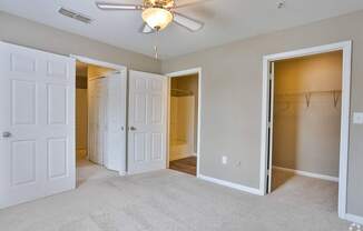 A room with a ceiling fan and four doors.