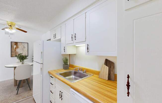 A kitchen with white cabinets and a wooden counter top.