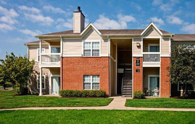 Two-story apartment building with green lawn and trees