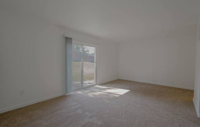 a living room with carpet and a sliding glass door